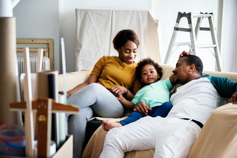A mother, father, and toddler relaxing together on the couch at home